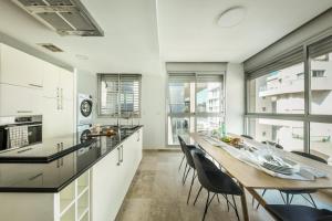 una cocina con una mesa de madera larga y sillas en Chic Apartment w Balcony, Mamad & Parking 3-min from Beach by Sea N' Rent en Tel Aviv