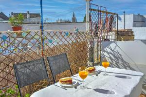 una mesa con 2 vasos de zumo de naranja en el balcón en Apartamento Casa Pilatos, en Sevilla