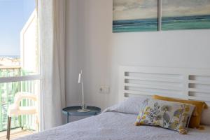 a white bedroom with a bed and a balcony at Bahia 653 in Nerja