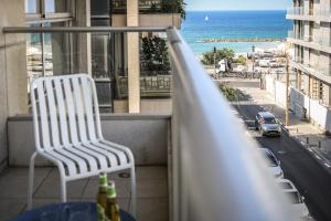 una silla blanca en el balcón con vistas al océano en Chic Apartment w Balcony, Mamad & Parking 3-min from Beach by Sea N' Rent en Tel Aviv