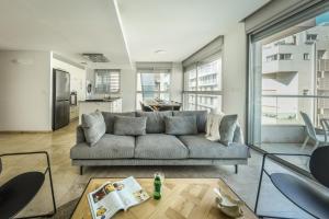 sala de estar con sofá y mesa en Chic Apartment w Balcony, Mamad & Parking 3-min from Beach by Sea N' Rent en Tel Aviv