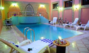 ein großer Pool mit Stühlen und einem Tisch in einem Gebäude in der Unterkunft Residence Hotel Assounfou in Marrakesch