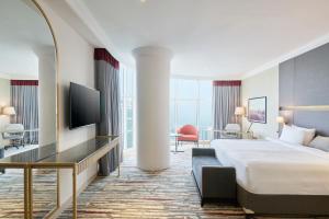 um quarto de hotel com uma cama e uma televisão em Ramada by Wyndham Doha Old Town em Doha