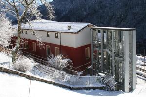 a red and white building with a gate in the snow at Foresteria Giardino in Paisco