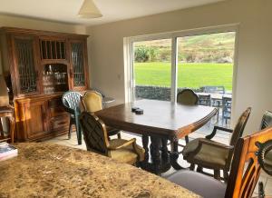 una sala da pranzo con tavolo, sedie e finestra di Valentia View Holiday Home a Cahersiveen