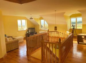 a living room with a staircase with a couch and a tv at Valentia View Holiday Home in Cahersiveen