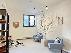 una sala de estar con 2 sillas y un árbol en Penzion 7 pokojů en Znojmo