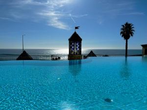 a swimming pool with a clock tower in front of the ocean at Lux Parede Ocean View in Parede