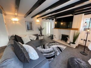 a living room with a gray couch and a fireplace at Tollgate House - Luxury Cozy Cottage - HUGE Hot Tub - Alton Towers in Cheadle