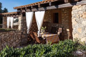 a patio with a table and chairs and a stone wall at Dammusi Ziunì in Lampedusa