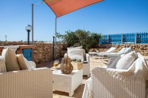 a patio with wicker chairs and a table with wine glasses at Dammusi Ziunì in Lampedusa