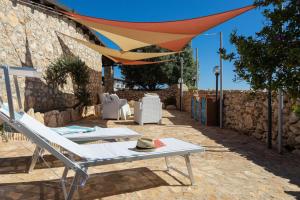 a patio with a hammock and a umbrella at Dammusi Ziunì in Lampedusa