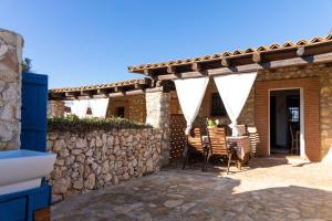 a patio with a stone wall and a table and chairs at Dammusi Ziunì in Lampedusa