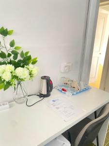 Un escritorio blanco con un jarrón de flores. en Best Rooms - Quarto 1 Plateau en Praia