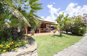 ein Haus mit einer Palme und einem Garten in der Unterkunft Villa Porticciolo vicino spiaggia per 6 persone con Aria Condizionata WiF in Santa Maria la Palma