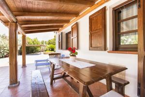 ein Esszimmer mit einem Holztisch auf einer Terrasse in der Unterkunft Villa Porticciolo vicino spiaggia per 6 persone con Aria Condizionata WiF in Santa Maria la Palma