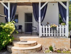 weranda z niebieskimi zasłonami i białym płotem w obiekcie Holiday Home Balatonszárszó w mieście Balatonszárszó +26 zdjęć