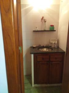 a bathroom with a sink and a wooden cabinet at NECOCHEA DEPARTAMENTO TIPO LOFT 4 PAX in Necochea