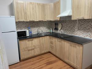 a kitchen with wooden cabinets and a white refrigerator at Уютная квартира на левом берегу Астаны in Taldykolʼ +7 photos