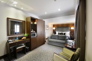 a hotel room with a couch and a bedroom at Park Grand London Kensington in London