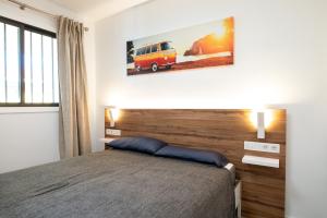 een slaapkamer met een bed en een foto van een busje aan de muur bij Black Sand Holiday Home in Puerto de Santiago