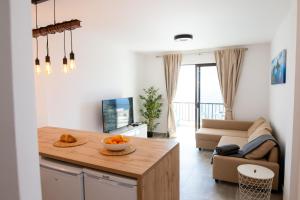 een keuken en een woonkamer met een tafel en een bank bij Black Sand Holiday Home in Puerto de Santiago