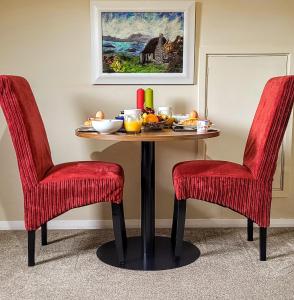 una mesa con sillas rojas y un bol de fruta en Self catering upper floor flat at Woodend house en Balmacara