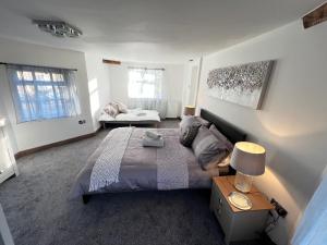 een slaapkamer met een bed en een tafel met een lamp bij Tollgate House - Luxury Cozy Cottage - HUGE Hot Tub - Alton Towers in Cheadle