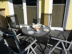 a table with cups and saucers on a balcony at Appartement Sundevit in Börgerende-Rethwisch