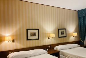 una camera d'albergo con due letti e due lampade di Hotel Ghironi a La Spezia Altre 37 foto