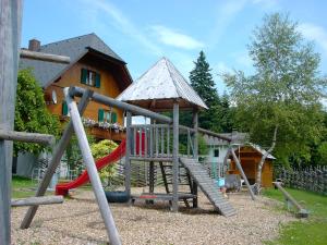 um parque infantil com escorrega em frente a uma casa em Pension Holzmeister em Sankt Kathrein am Offenegg