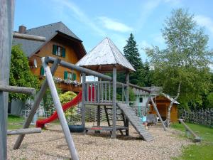 a playground with a slide in front of a house at Pension Holzmeister in Sankt Kathrein am Offenegg