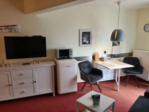 ein Wohnzimmer mit einem TV, einem Tisch und Stühlen in der Unterkunft Strandburg Juist Apartment 208 - Schwimmbad und Sauna kostenfrei in Juist