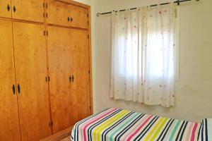 1 dormitorio con cama, armarios de madera y ventana en Chalet Cortijo 31, en Conil de la Frontera