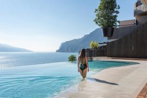 a woman standing in the water next to a swimming pool at EALA My Lakeside Dream - Adults Friendly in Limone sul Garda