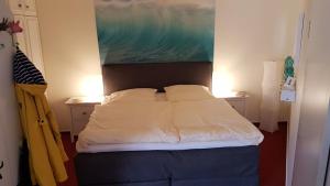 ein Schlafzimmer mit einem Bett mit zwei Kissen und einem Gemälde in der Unterkunft Strandburg Juist Apartment 208 - Schwimmbad und Sauna kostenfrei in Juist