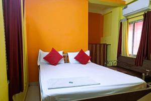 een slaapkamer met een wit bed met rode kussens bij Trinayani Stay - 3 min Walk to Temple in Tarapith