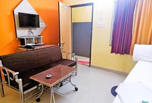 een ziekenhuiskamer met een tafel, een bed en een tv bij Trinayani Stay - 3 min Walk to Temple in Tarapith