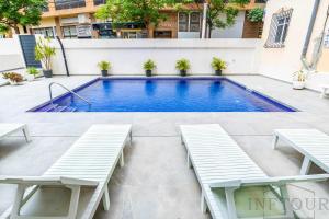einem Pool mit Bänken vor einem Gebäude in der Unterkunft Inftour Primavera Apartamento in Calpe