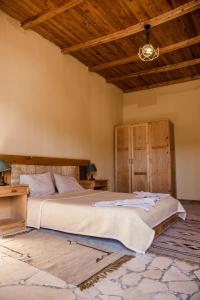 une chambre avec un grand lit et un plafond en bois dans l'établissement Dehiba Siwa Resort, à Siwa