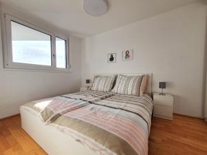 een witte slaapkamer met een bed en een raam bij Near Lake Stylish & Fully Furnished Apartment in Wenen
