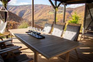 a wooden table on a deck with a view of mountains at Amonte Mountain Resort in Muntele Rece