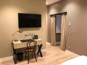 a bedroom with a desk and a television on a wall at Caruso Place Boutique & Wellness Suites in Naples