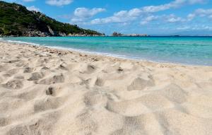 una spiaggia con impronte di piedi nella sabbia e nell'oceano di Apartments in Santa Teresa di Gallura a Santa Teresa di Gallura