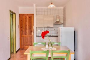 una cucina con tavolo e fiore rosso in vaso di Apartments in Santa Teresa di Gallura a Santa Teresa di Gallura