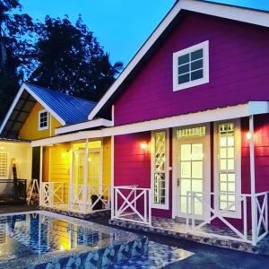 uma casa vermelha e amarela com uma piscina em frente em Cheqma Tiny Chalet em Kota Bharu