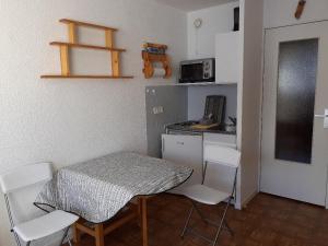 a small kitchen with a table and white chairs at Studio au Sauze avec balcon, parking et équipements tout confort - FR-1-165A-114 in Enchastrayes
