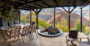 una terrazza con tavolo, sedie e vista sulle montagne di Amonte Mountain Resort a Muntele Rece