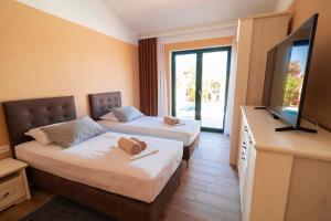 pokój hotelowy z 2 łóżkami i telewizorem z płaskim ekranem w obiekcie Sea Cats' Villas w mieście Sutivan