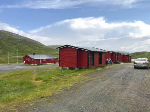 ein Auto, das neben einer Reihe roter Gebäude parkt in der Unterkunft Hytte Camp Nordkapp - Red in Skarsvåg